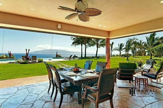 View from Lanai looking out to the ocean with palm trees and outdoor dining area.