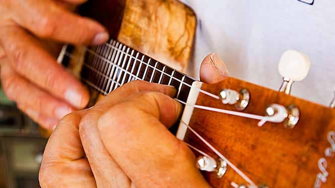 Closeup of Man's fingers playing ukulele