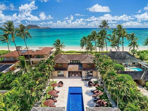 Aerial view of a luxury home in Kailua with pool, home, beach, and palm trees.